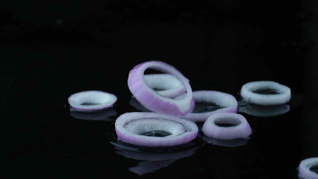 ⁇ 어낸 양파 반지는 기름으로 검은 팬에 떨어집니다.