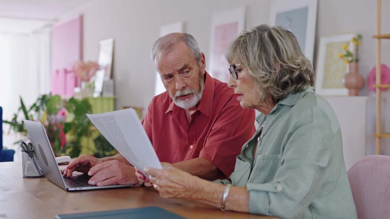 Elderly couple working on laptop at home