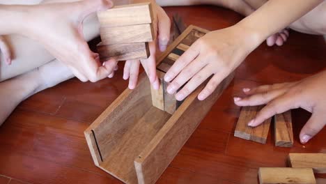 multiple hands solving a wooden block puzzle together