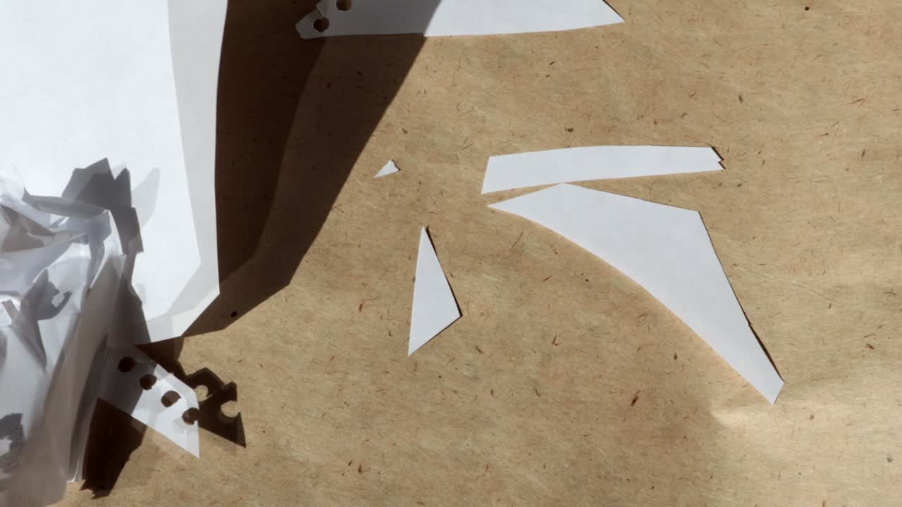 video 4k, fotografía macro de hojas blancas arrugadas volando lejos del viento sobre el fondo de papel kraft marrón