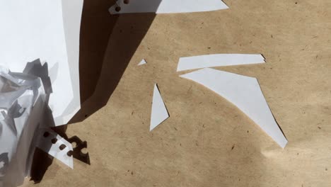 4k video, macro photography of crumpled white sheets flying away from the wind on the background of brown kraft paper