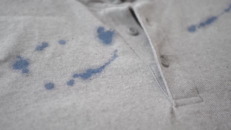 close up of a grey polo shirt with blue ink stains