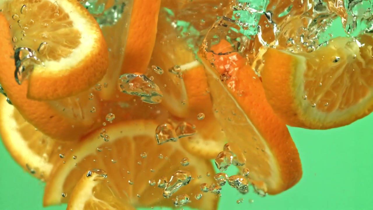 Frische Orangenscheiben spritzen ins Wasser mit Blasen