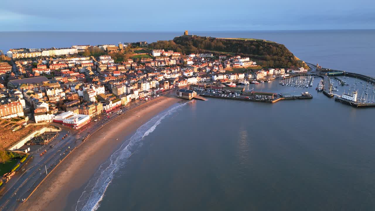 Ripresa aerea in parallasse di una città vecchia con una piccola collina accanto al porto con barche a Scarborough, North Yorkshire, Inghilterra