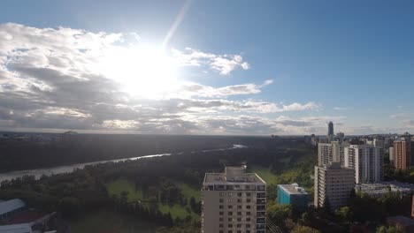 bunched up clouds dissipating during a sunset over a valley park seperated by a massive wide river between a residential downtown community and the other side being a university campus with vip homes