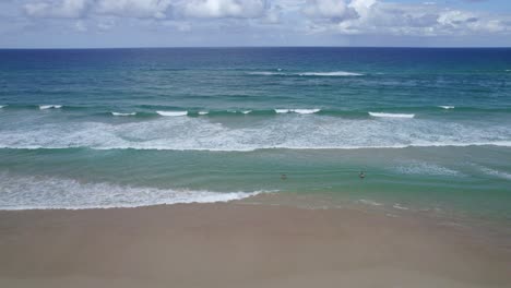 Gente-Nadando-En-El-Mar-Con-Olas-Rodando-Hacia-La-Orilla-Arenosa-En-La-Playa-De-Miami,-Destino-Famoso-En-La-Costa-Dorada,-Queensland