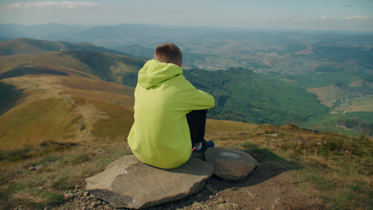 Young Guy Sitting on Stone and Watching on Landscape Young Guy Sitting on Stone Watching on Beautiful Landscape Feeling Breath of Warm Wind Frees Thoughts and Relaxing Spending Leisure Time Outdoor Face Closeup View