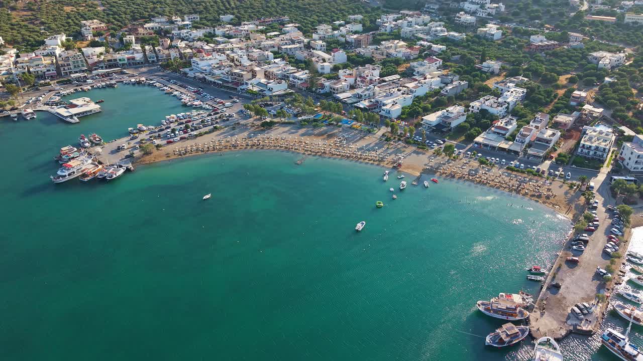 Orbiting aerial shot of the scenic port and beach of Elounda, Crete at sunset