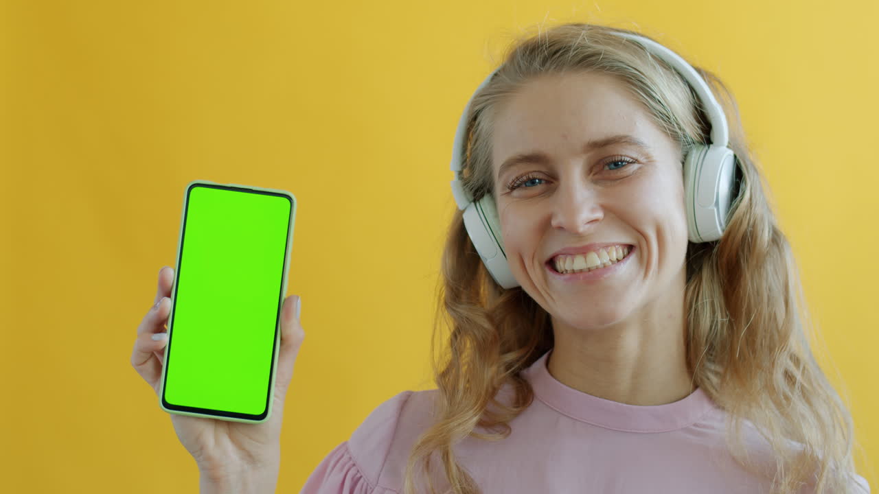 Woman with headphones and green screen phone
