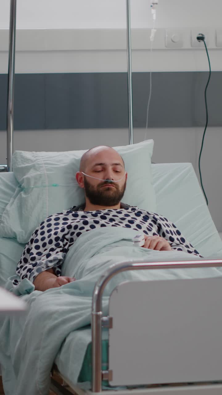 Vertical video: Practitioner asisstant arrange patient bed to sick man during sickness recovery