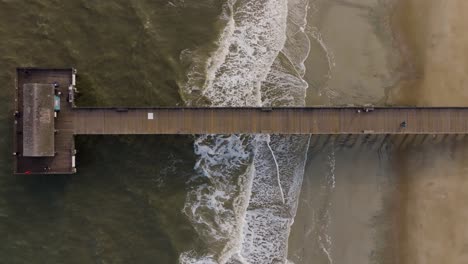 Drone-De-Una-Playa-Vacía-En-La-Isla-Tybee-Sobre-Un-Muelle-Con-Pájaros-Volando-Y-Olas-Rompiendo