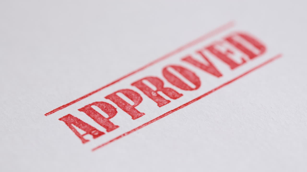 A stamp Approved is placed on a sheet of white paper, close-up