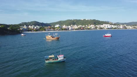 aerial dolly out shot of fishing boats working on the sea near bombinhas beach, brazil