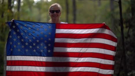Closeup-of-a-pretty-mature-woman-wearing-sunglasses-and-smiling-plays-with-an-American-flag-by-waving-it-up-and-over-her-head-and-then-down-in-front-of-her