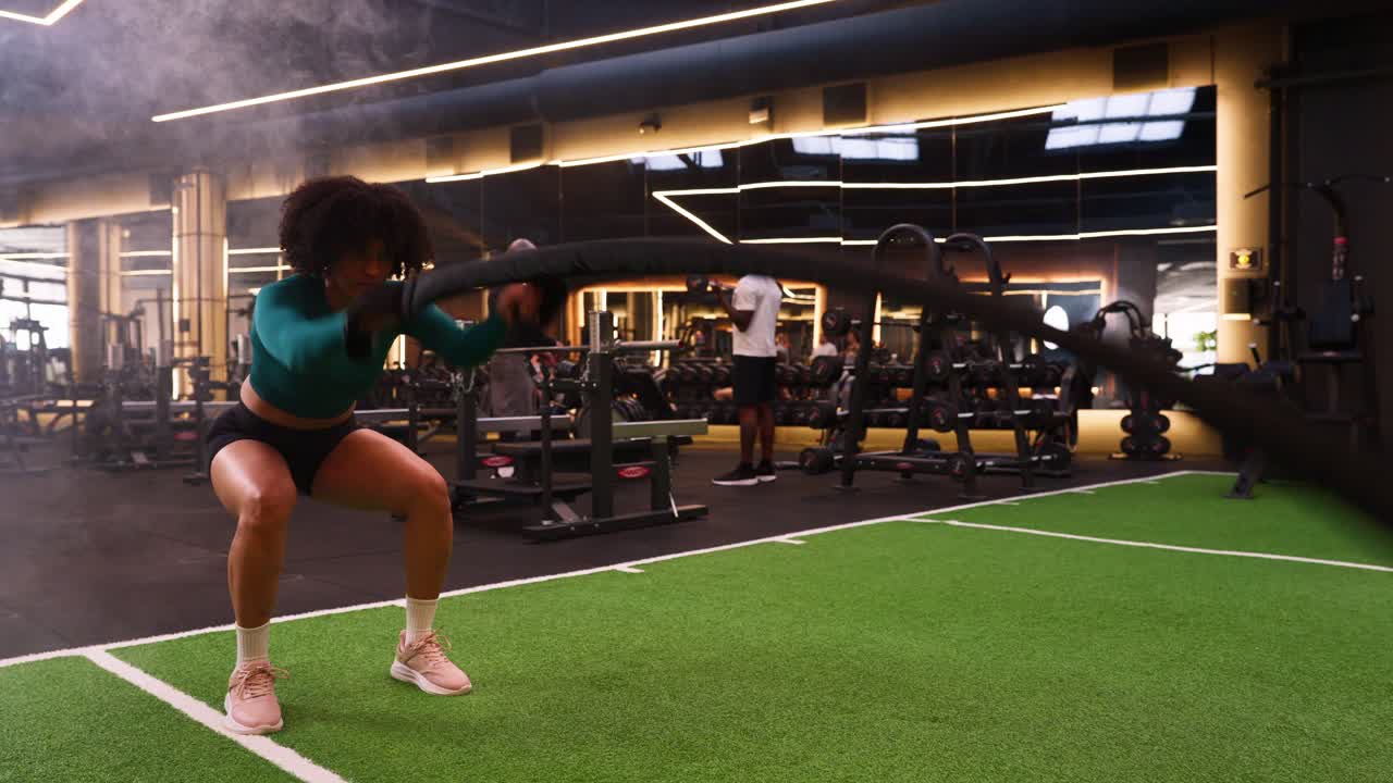 Mulher forte treinando com cordas navais em uma academia moderna