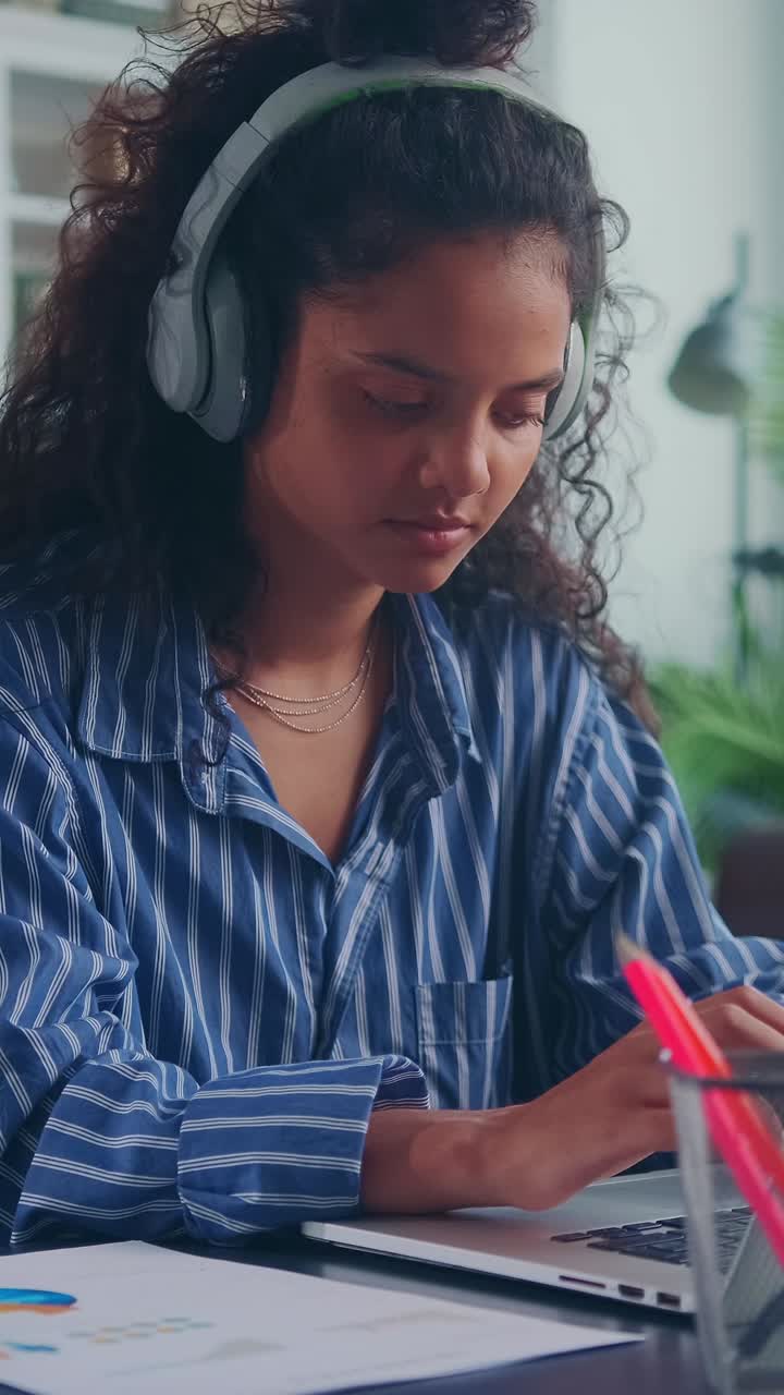Young woman focused on studying while wearing headphones indoors