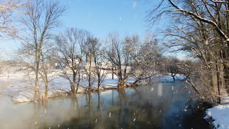 AERIAL-Revealing-Mystical-Rural-River-With-Leafless-Trees-During-Snowfall