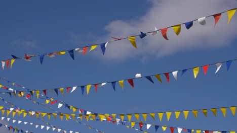 multicolored triangle flags for party waving on wind on blue sky background. background plate, chroma key video background