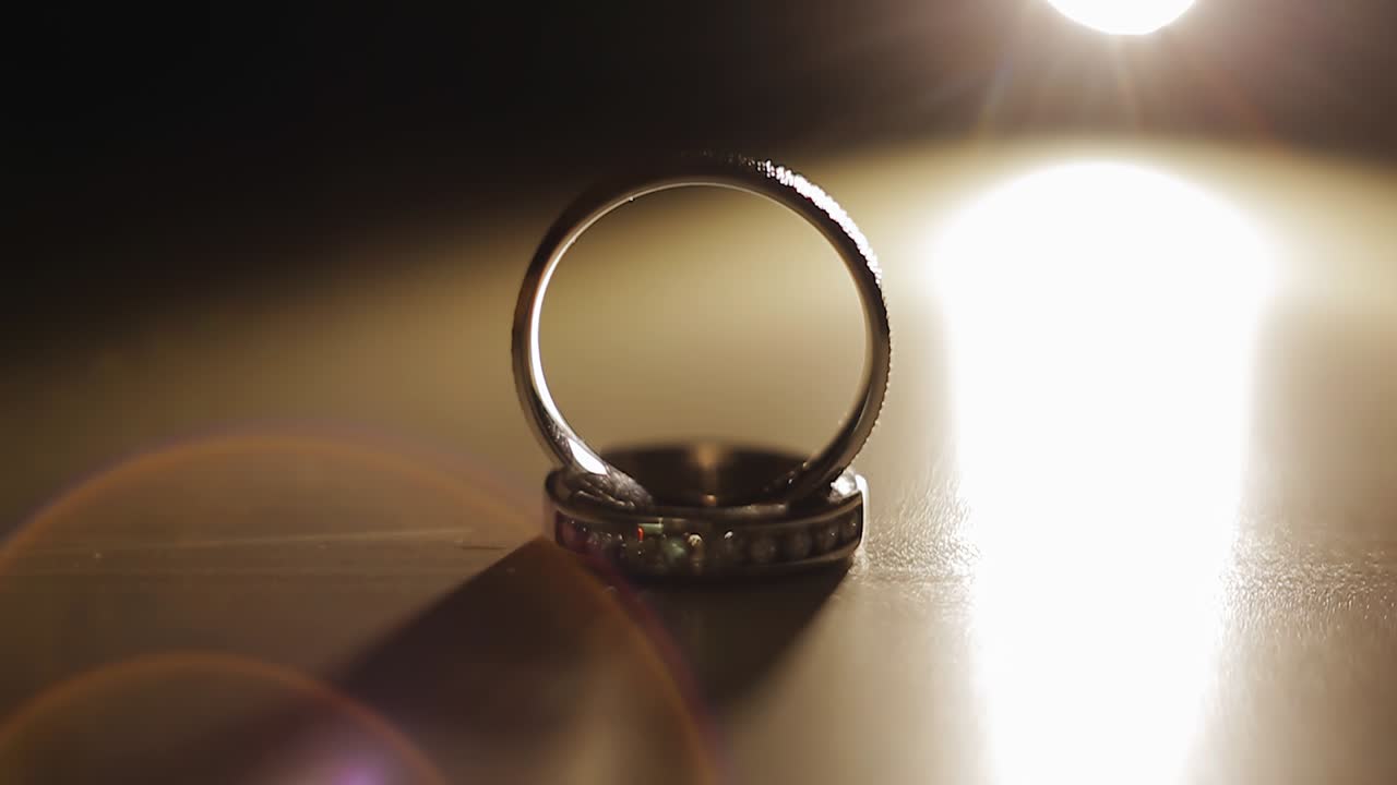 Dynamic light illuminates the precious wedding rings standing on the surface. Close-up shooting