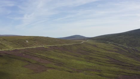 aerial view of cars driving on a long, winding mountain road in the wicklow mountains on a sunny day-2