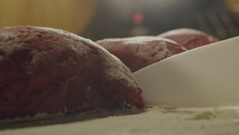 a person hand cutting red cookie dough with a white plastic knife, close up static