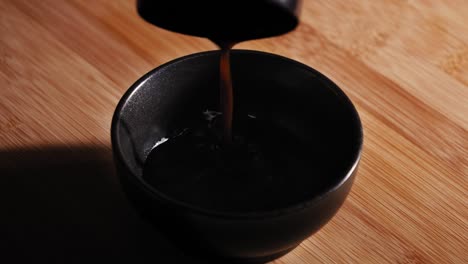 pouring soy sauce, worcester sauce, and water into a bowl then add a teaspoon of black pepper