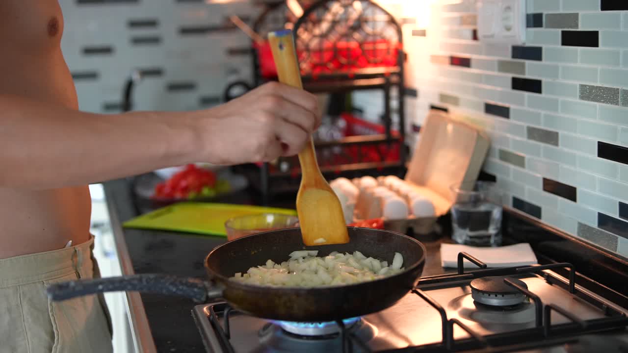 persona cocinando cebollas en una sartén