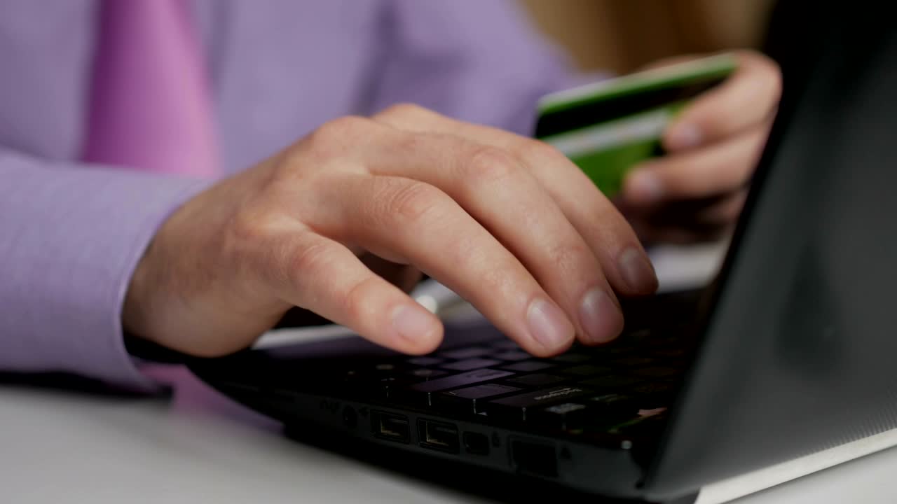 un hombre de negocios con una camisa púrpura y corbata está haciendo un pago a la banca por internet. compras en línea con tarjeta de crédito en la computadora portátil.