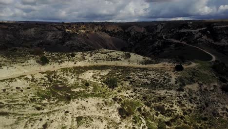 wide aerial view of a group of runners who are jogging up a path on the side of the mountain in akamas in cyprus paphos