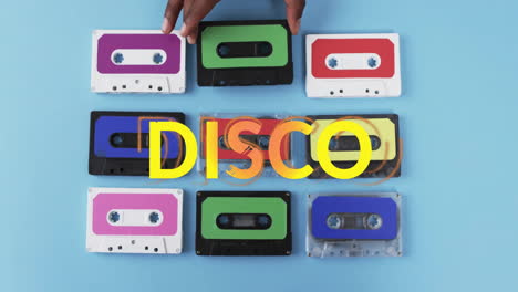 animation of yellow disco text over hand of african american woman holding tape on blue background