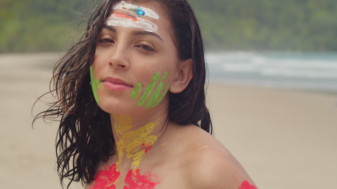 A sunny day in the Caribbean sees a girl adorned in body paint and a bikini on a white sand beach