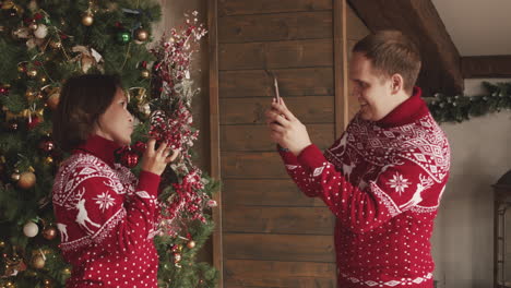 man taking a funny video of his wife while she holding a christmas wreath at home 1