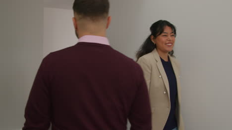 male and female teachers passing as they walk along corridor in school building together 2