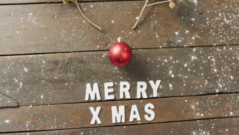 Video-of-christmas-greetings-text-and-bauble-decoration-on-wooden-background
