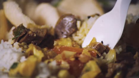 Extreme-closeup-of-white-plastic-spoon-scoops-a-bite-of-southeast-asian-food