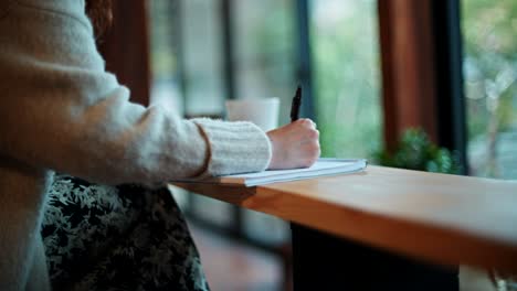 woman writing in a cafe