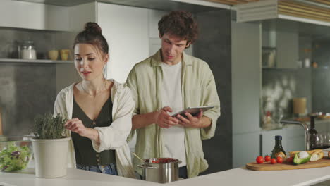 young couple cooking together in a modern kitchen using a tablet