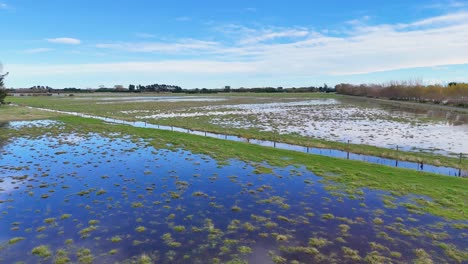 aerial view of flooded fields in christchurch, showcasing waterlogged landscapes under clear blue skies