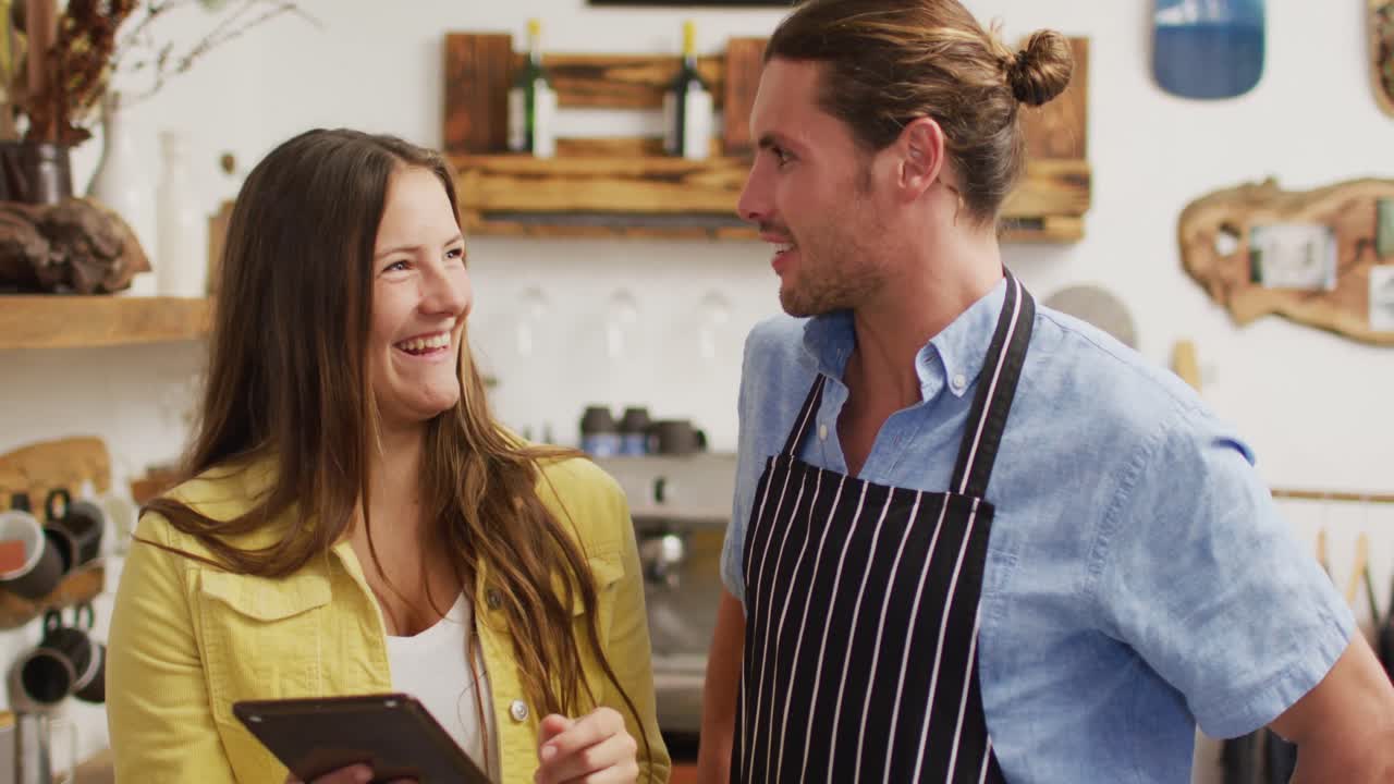 video de un feliz vendedor caucásico en una cafetería y la propietaria con una tableta