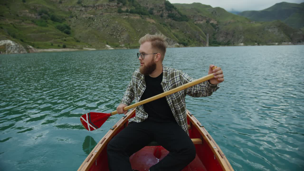 hombre remando una canoa en un lago de montaña
