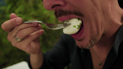 man eating mozzarella from the pizza with the fork during dinner