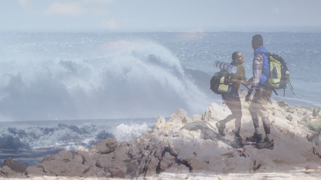 man and woman hiker standing on outcrop near ocean holding backpacks, showing animated health graph