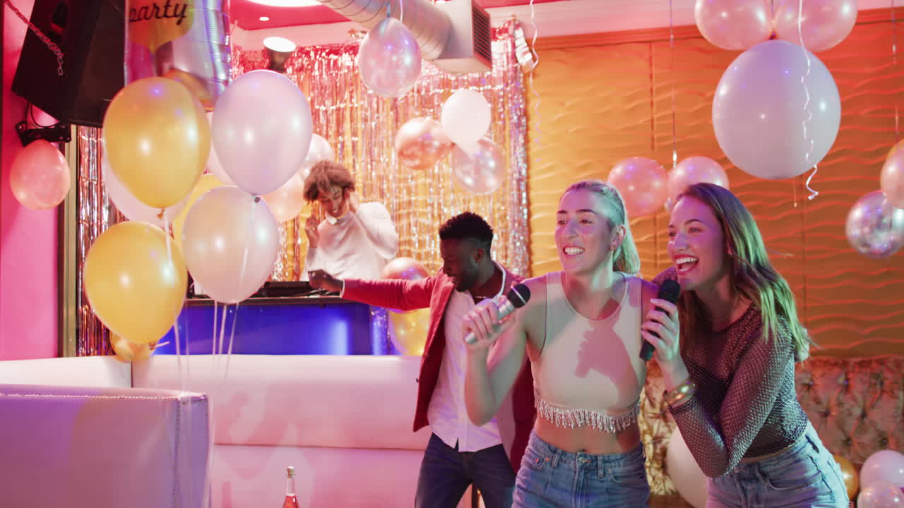 Video of two happy caucasian female friends singing karaoke at a nightclub bar