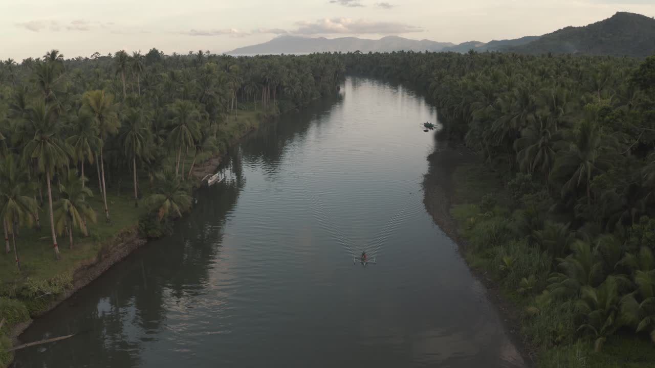 barco de pesca local navegando en el tranquilo arroyo de agua con reflejos de bosque de árboles verdes durante la madrugada en la provincia insular de filipinas