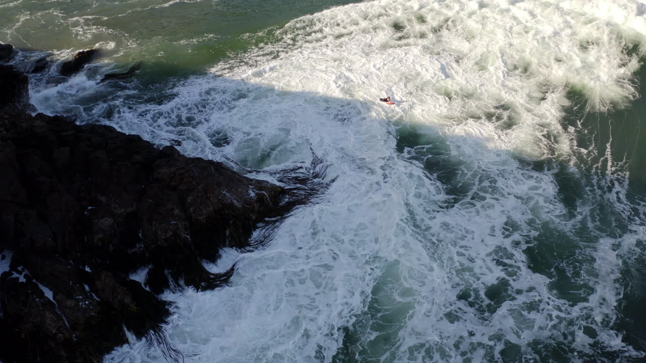 Kayaker in rough sea near rocky coast