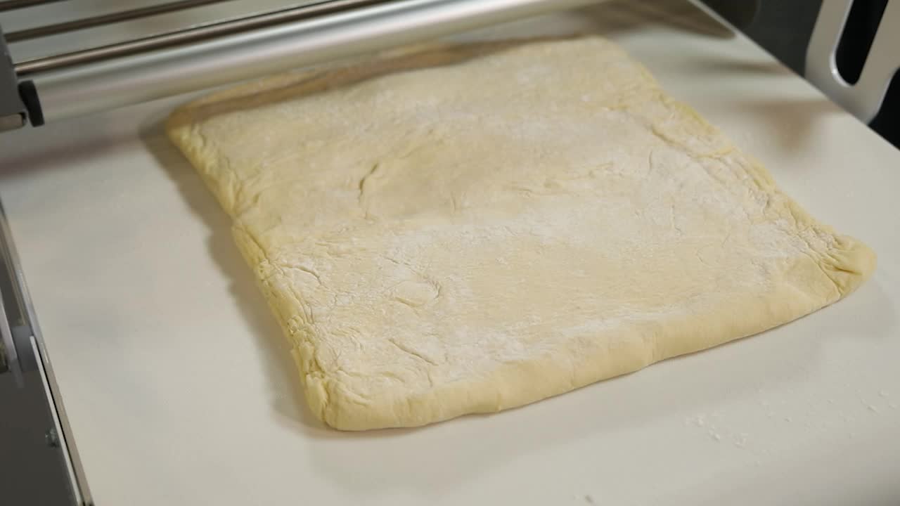Dough being processed by a rolling machine