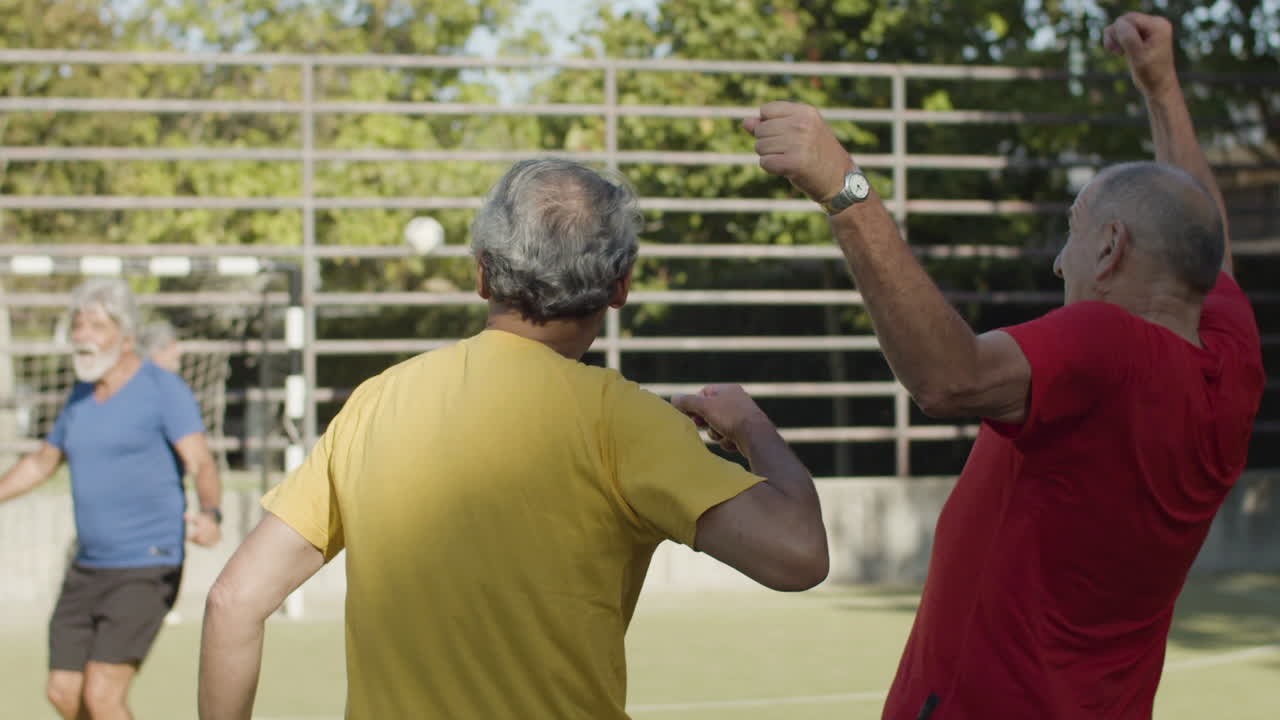 원을 그리며 포옹하고 함께 목표를 축하하는 행복한 시니어 축구 선수 팀