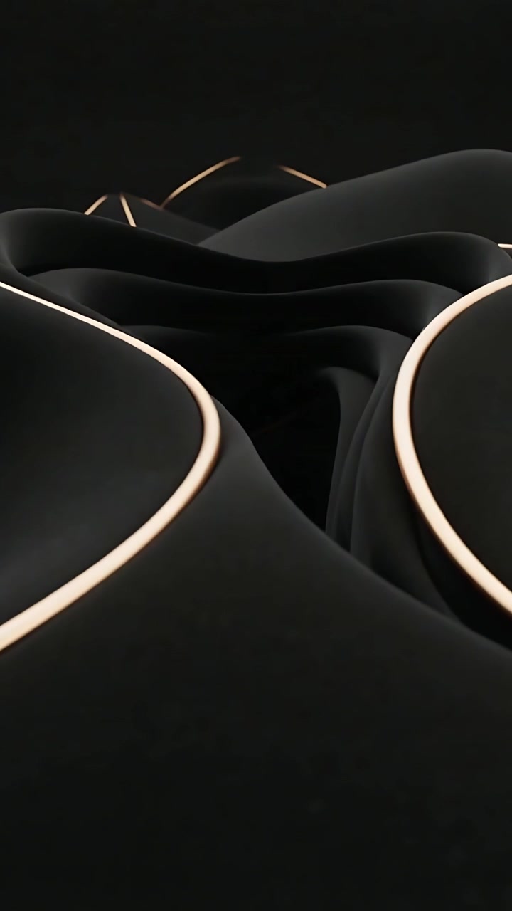 Video vertical: Cámara moviéndose hacia formas plegadas de color negro mate en un vacío oscuro, revelando costuras de oro cálido