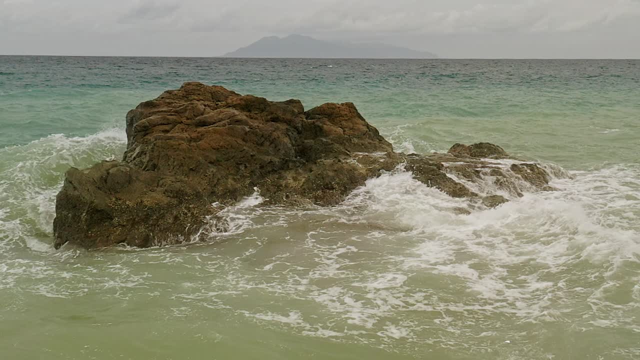 Roccia della spiaggia di Banbanon al rallentatore con le onde che si infrangono creando spruzzi a Surigao Del Norte, Filippine