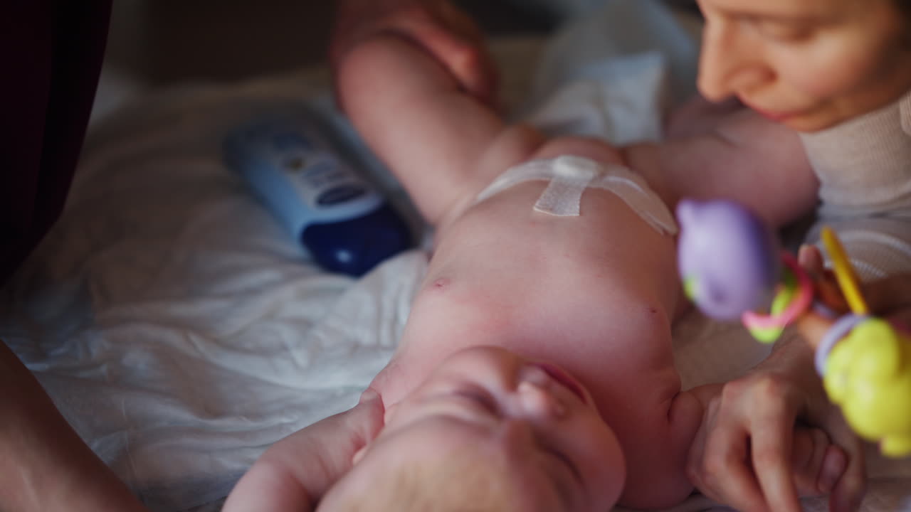 Assistente che fa esercizi di mobilità con un neonato, distratto da un giocattolo.